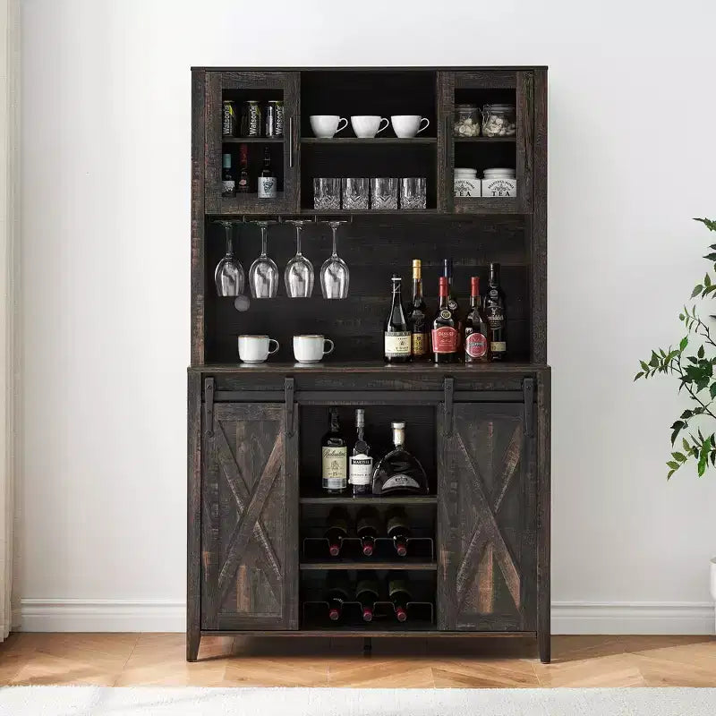 Dark wood bar cabinet with shelves displaying bottles, glasses, and cups against a white wall.